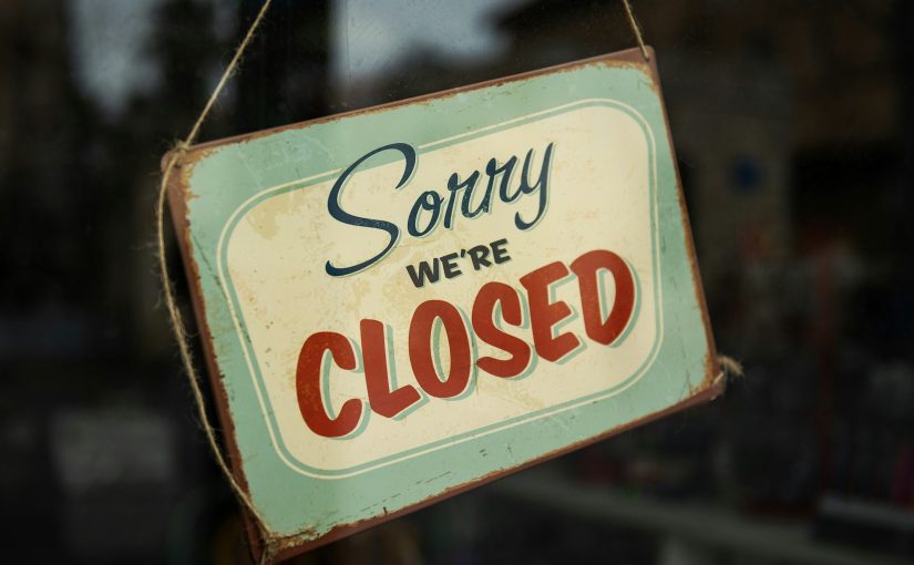 Ein altes Blechschild mit der Aufschrift Sorry we are closed hängt in einem Schaufenster